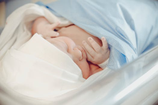 A serene newborn baby sleeping in a hospital, wrapped in a blue blanket.